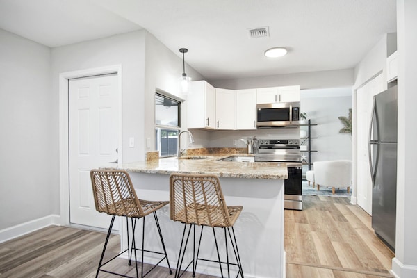 Modern kitchen with granite island, bar stools & stainless appliances