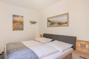 A bedroom with a bed, two paintings, and a wall-mounted sign. - Emil Vacation Rental with Sauna, Garden, and Sun Deck - Cozy (Garz)