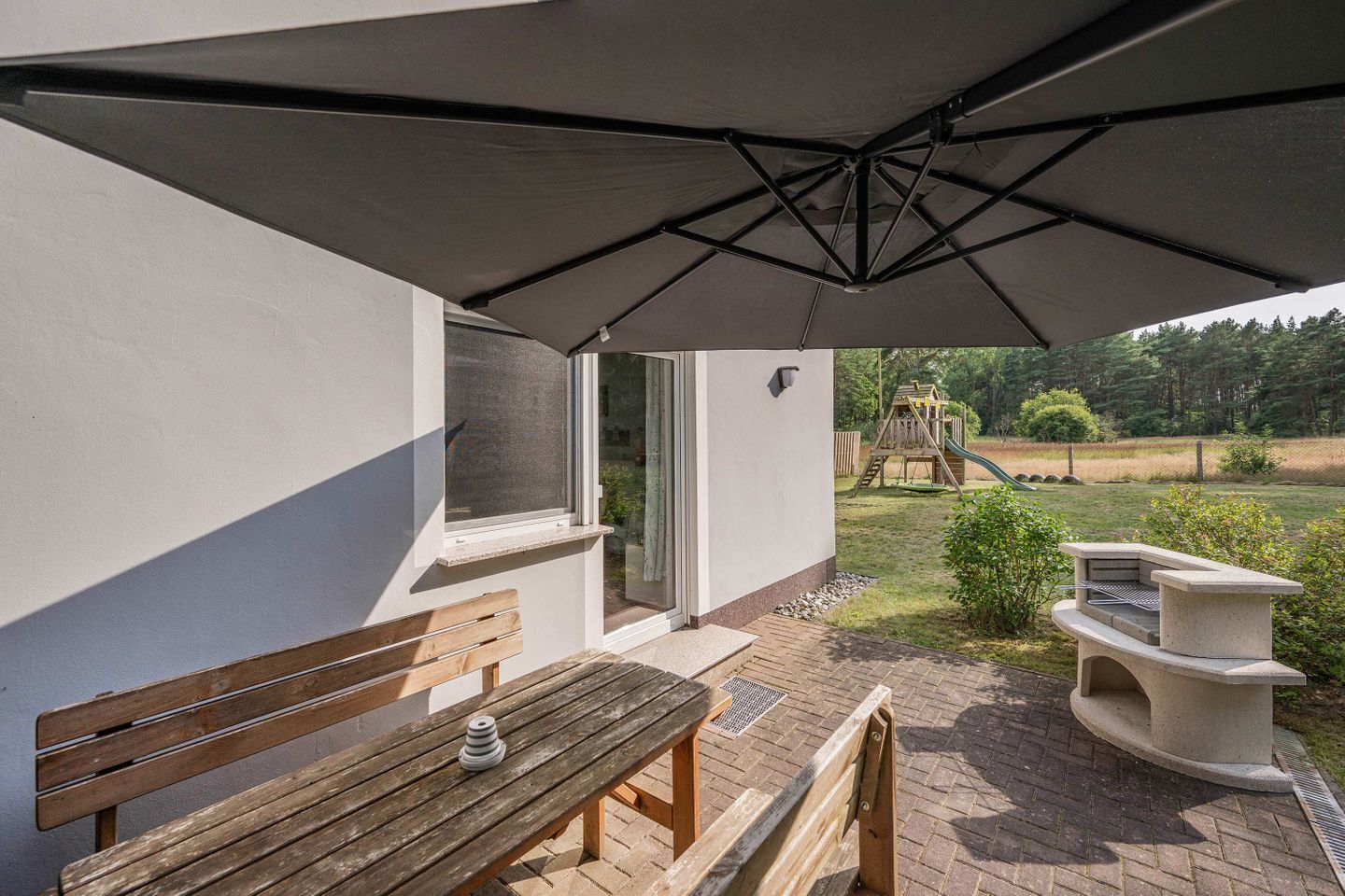 Eine Terrasse im Freien mit einer Holzbank, einem Tisch und einem Grill.