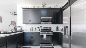 A modern kitchen with dark cabinets, stainless steel appliances, and a black and white color scheme. - Spacious 4-bedroom house in marvelous Las Conchas with AC, WiFi (Las conchas)