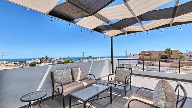 A rooftop terrace with outdoor seating, a view of the sea, and buildings in the background. - Spacious 4-bedroom house in marvelous Las Conchas with AC, WiFi (Las conchas)