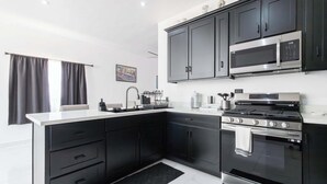 A modern kitchen with black cabinets, a stainless steel microwave, and a gas stove. - Spacious 4-bedroom house in marvelous Las Conchas with AC, WiFi (Las conchas)