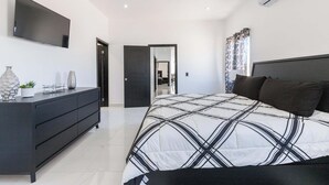 A modern bedroom with a bed, a dresser, a TV, and a ceiling fan. - Spacious 4-bedroom house in marvelous Las Conchas with AC, WiFi (Las conchas)