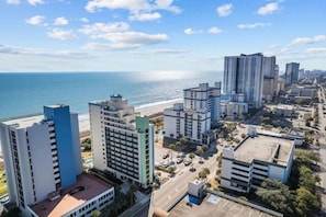 Un paysage urbain côtier avec de hauts immeubles, une plage et un ciel dégagé.