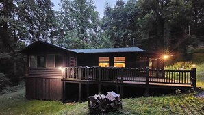 A cabin with a deck, a covered area, and a stack of firewood. - Private couples retreat/pet friendly/early checkin (Pigeon Forge)