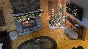 Una sala de estar acogedora con chimenea de piedra, un árbol de Navidad y un espacio de descanso cómodo.