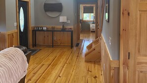 Amplio dormitorio tipo loft con piso de madera, cama grande, tragaluz y zona de descanso elevada.