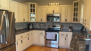 Una cocina moderna con armarios blancos, electrodomésticos de acero inoxidable y piso de madera.