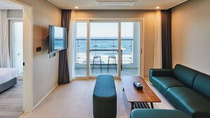 Une chambre d’hôtel avec un balcon, un lit, un canapé, une table et une télévision.