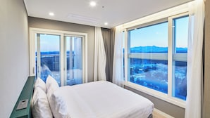Une chambre d’hôtel moderne, dotée d’un grand lit, d’un bureau et offrant une vue sur le paysage urbain grâce à de grandes fenêtres.