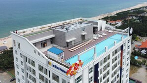Un hôtel doté d’une piscine sur le toit, offrant une vue sur la plage, et sur lequel on peut lire l’inscription « Le Bateau Naksas ».