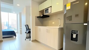 Una cocina moderna con armarios blancos, microondas integrado y un refrigerador de acero inoxidable.