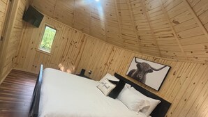 Puupaneloitu huone, jossa on sänky, yöpöytä, lamppu ja seinällä oleva kehystetty kuva.