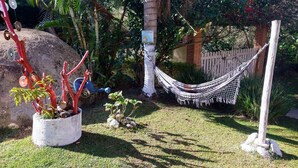 A garden with a hammock, a potted plant, and a blue watering can. - Suit Aconchegante Rústica (Mairiporã)