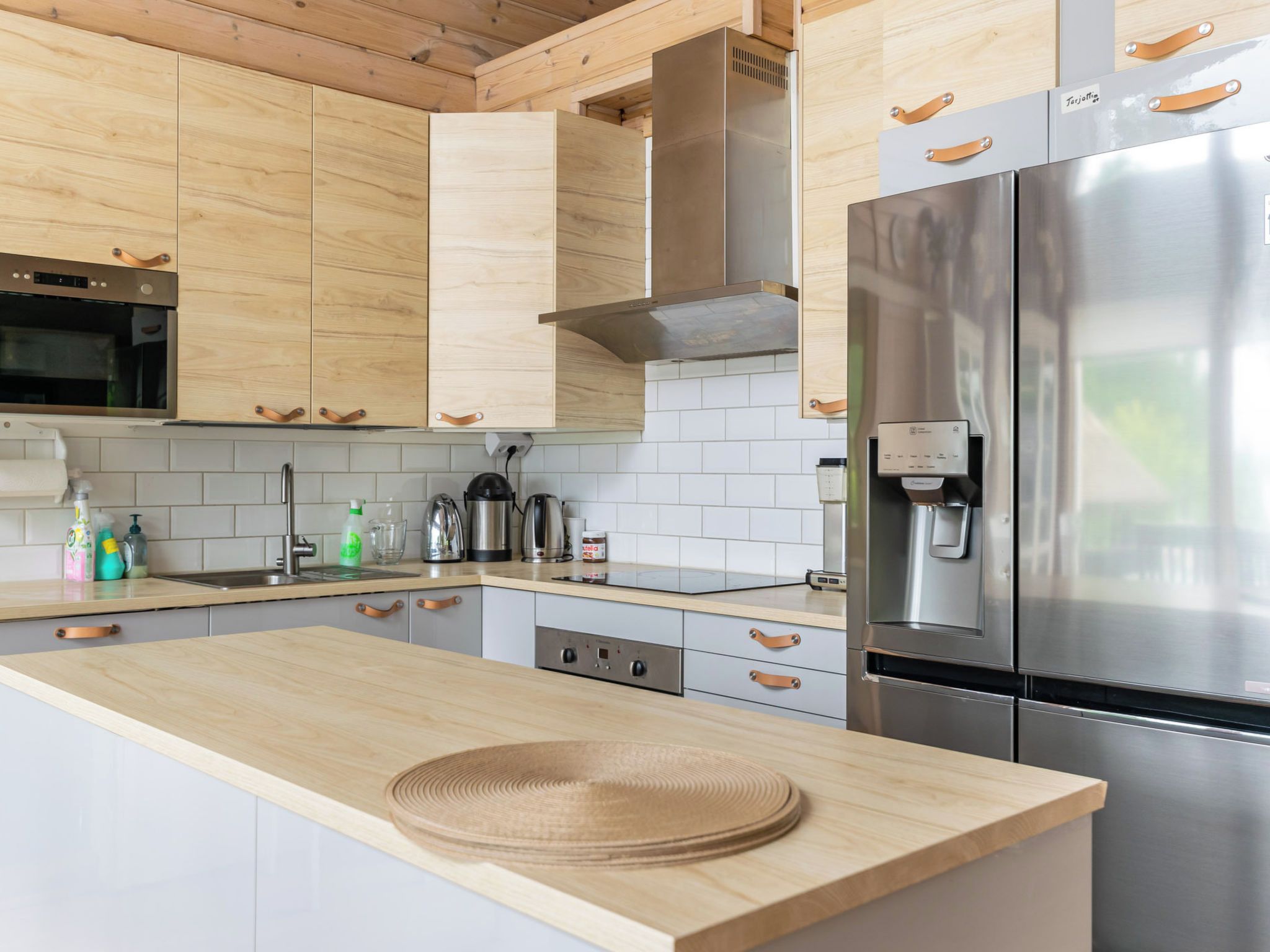 Eine moderne Küche mit Holzschränken, Edelstahlgeräten und einer Kaffeemaschine.
