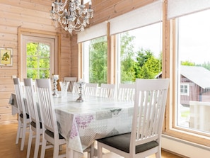 A dining area with a large table, white chairs, and a chandelier. - Villa sirpia by Interhome (Lohja)
