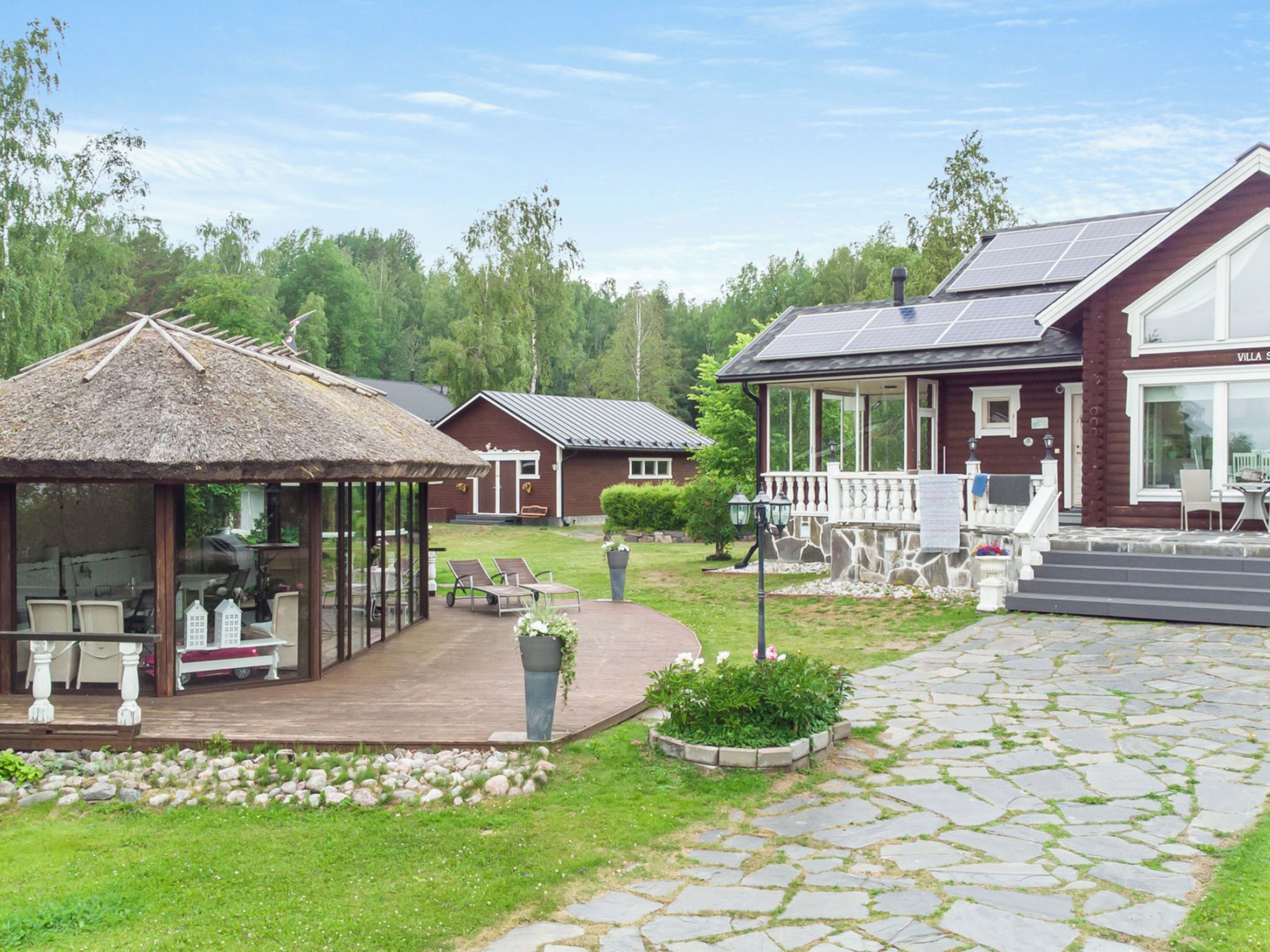 A resort with a thatched-roof structure, a covered outdoor seating area, and a building with solar panels.