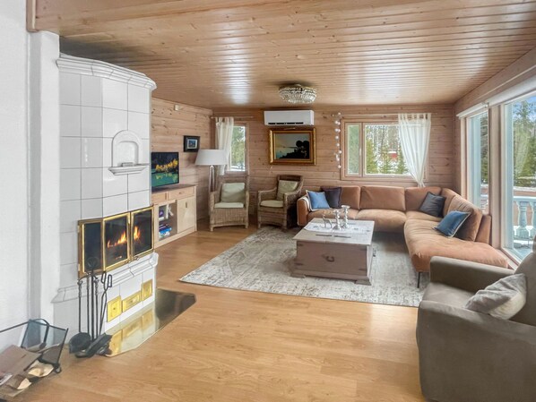 A cozy cabin-style room with a fireplace, wooden walls, a sofa, and a television.