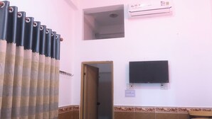 Ein Badezimmer mit Duschvorhang, Toilette, Waschbecken, Spiegel und einem an der Wand befestigten Fernseher.