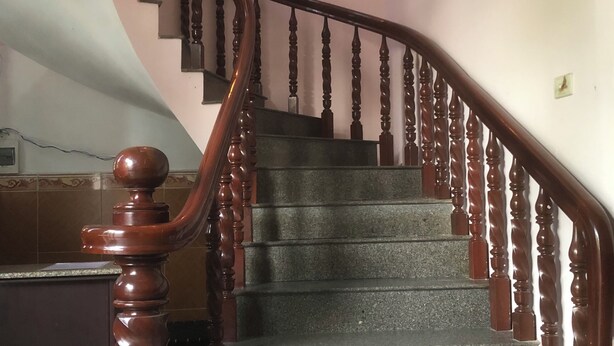Eine Treppe mit hölzernen Spindeln und einer Handlauf, die zu einer oberen Etage führt.