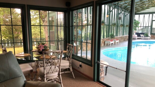 Une pièce dotée de grandes fenêtres, d’une piscine et de mobilier d’extérieur.