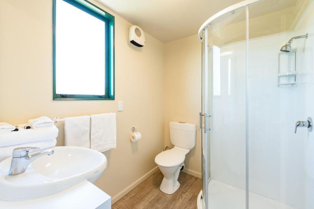 A bathroom with a sink, toilet, and glass shower enclosure.