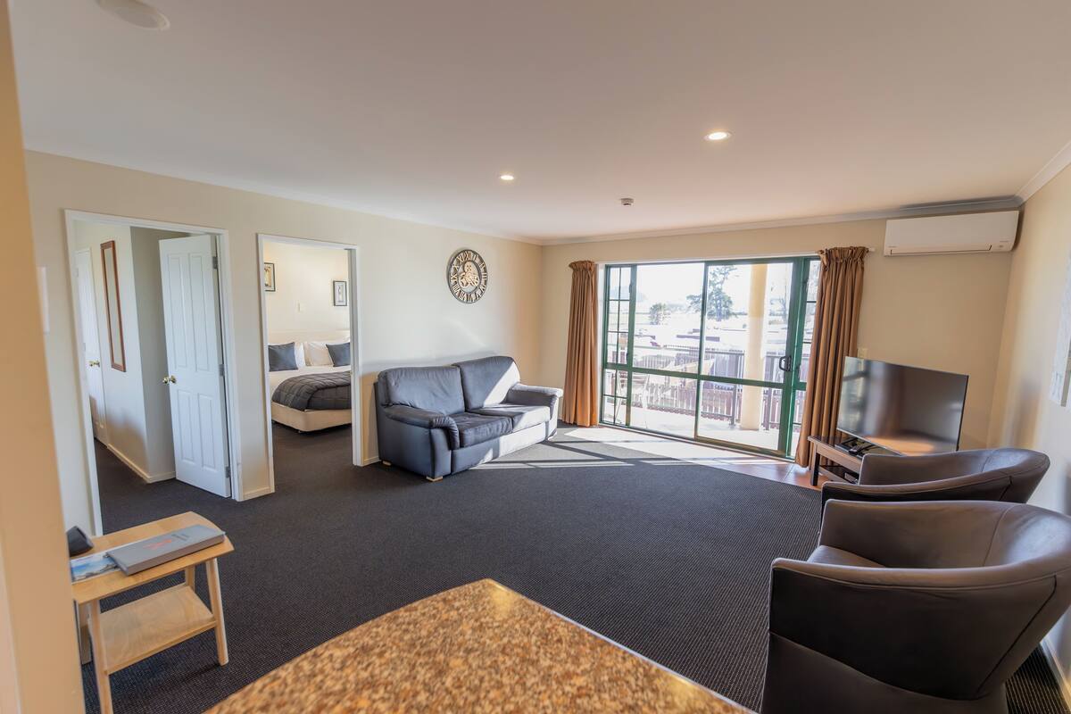 A modern living room with a sofa, a TV, and a view of the city through large windows.