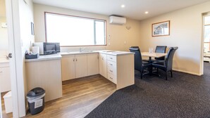A compact kitchen with a microwave, sink, and a dining area with chairs and a table. - Lobster Inn Motel (Kaikoura)