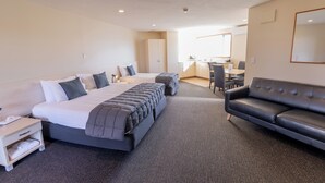 A hotel room with a large bed, a sofa, a desk, and a kitchenette. - Lobster Inn Motel (Kaikoura)