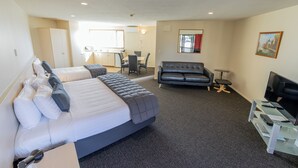 A hotel room with a large bed, a sofa, a desk with a computer, and a TV. - Lobster Inn Motel (Kaikoura)