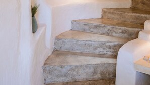 Una escalera con una pared texturizada, una ventana pequeña con cortina y una puerta de madera.