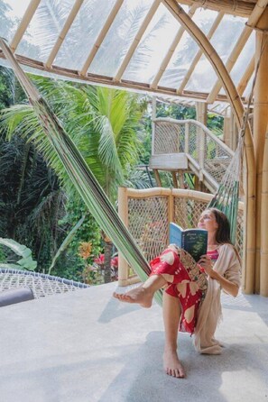 A person relaxing on a hammock in a bamboo structure with a view of lush greenery. - Bamboo Dream Villa by Betterplace (Ubud)