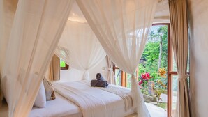 Un dormitorio con cama a dosel, vista al jardín y un ventanal grande.