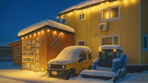A yellow house with a snow-covered roof and a sign reading "YELLOW HOUSE NSEKD". - Yellow House Niseko (Kutchan)