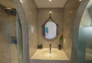 Un baño moderno con un espejo redondo, un lavabo y una zona de ducha.