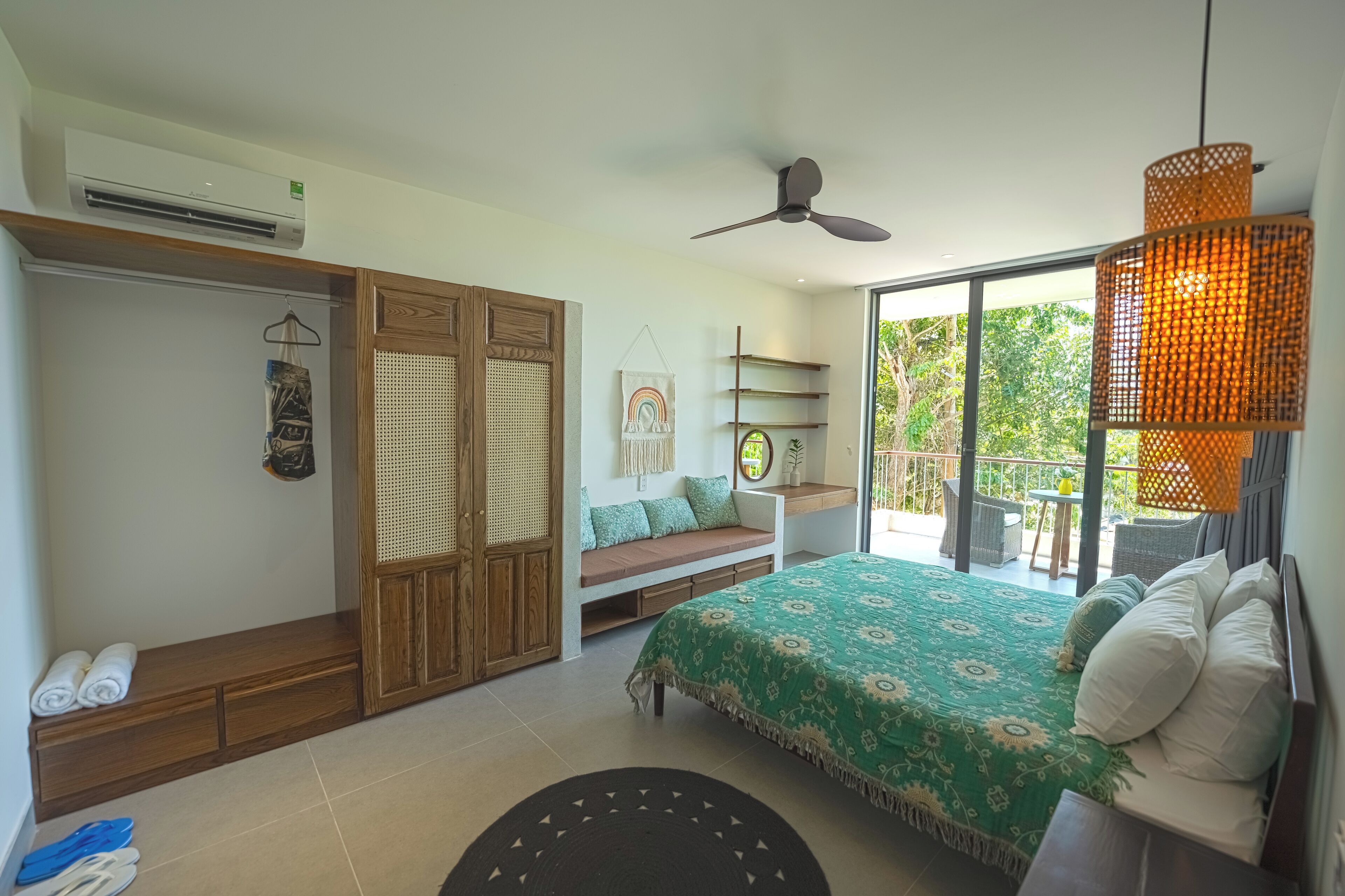 A bedroom with a bed, a bench, a wardrobe, and a balcony with outdoor furniture.