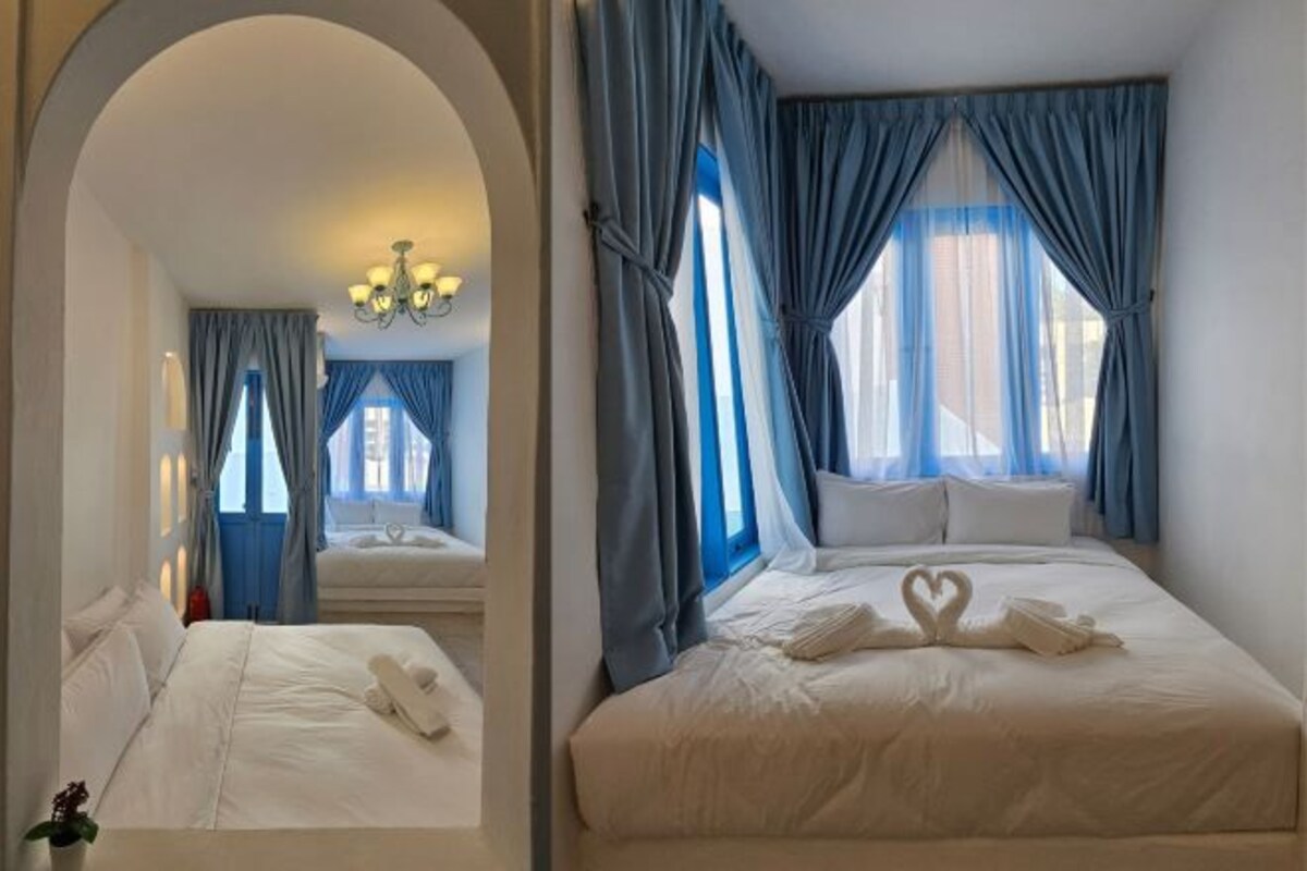 A hotel room with a large bed, a sitting area with a sofa, and a view of the outdoors through the window.