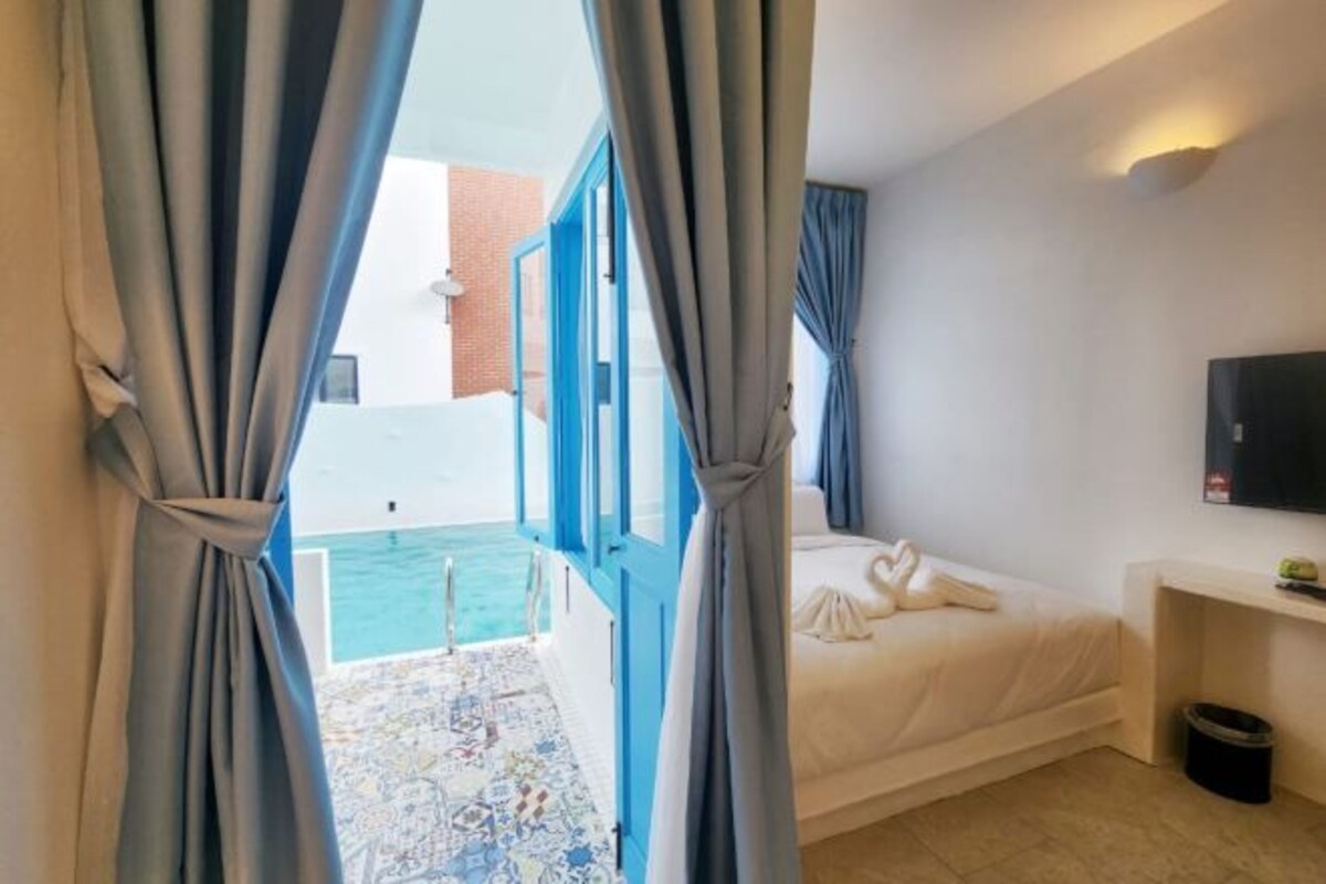 Una camera d'albergo con un letto, una televisione e vista sulla piscina.