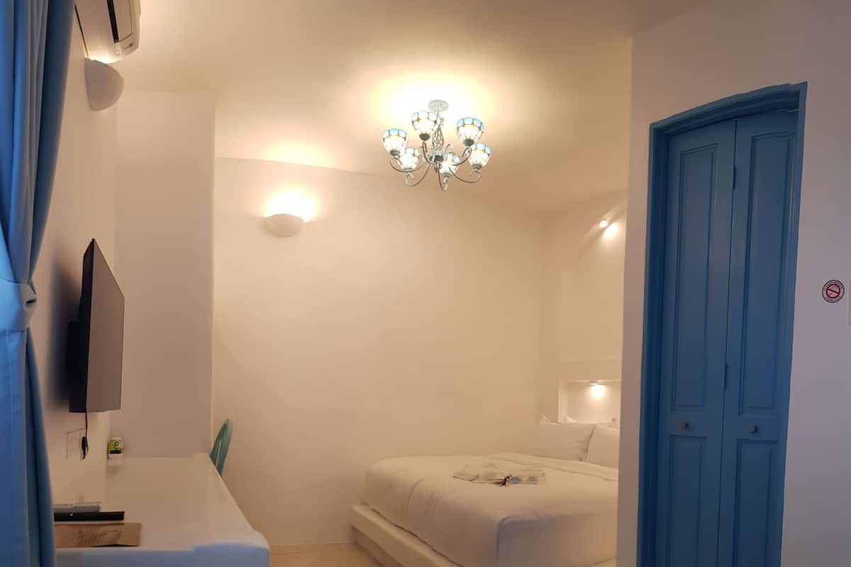 Ein Schlafzimmer mit Bett, Schreibtisch, Stuhl, einer Kandelaber und einer Tür.
