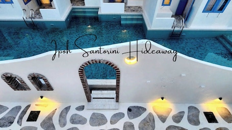 A pool area with steps leading into the water, a tiled archway, and wall-mounted lights.
