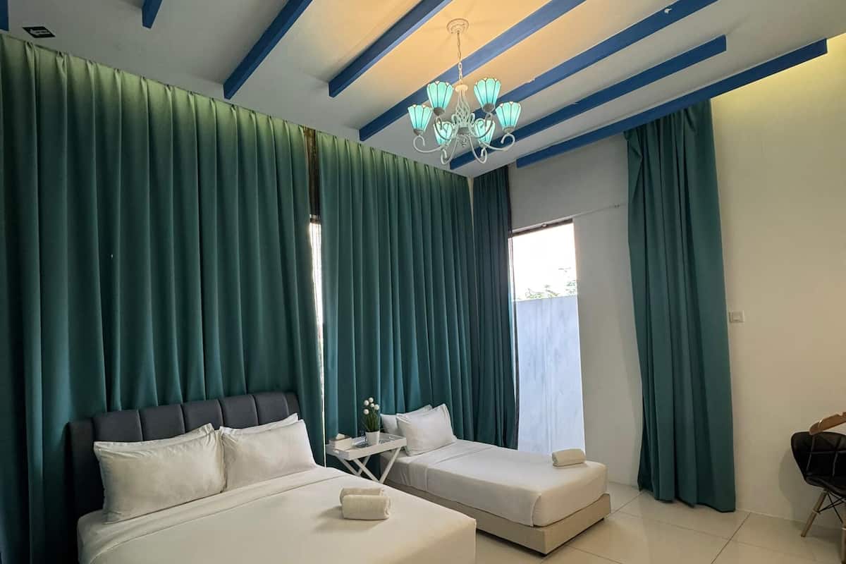 Ein Hotelzimmer mit zwei Betten, einer Kandelaber, grünen Vorhängen und einem Fliesenboden.