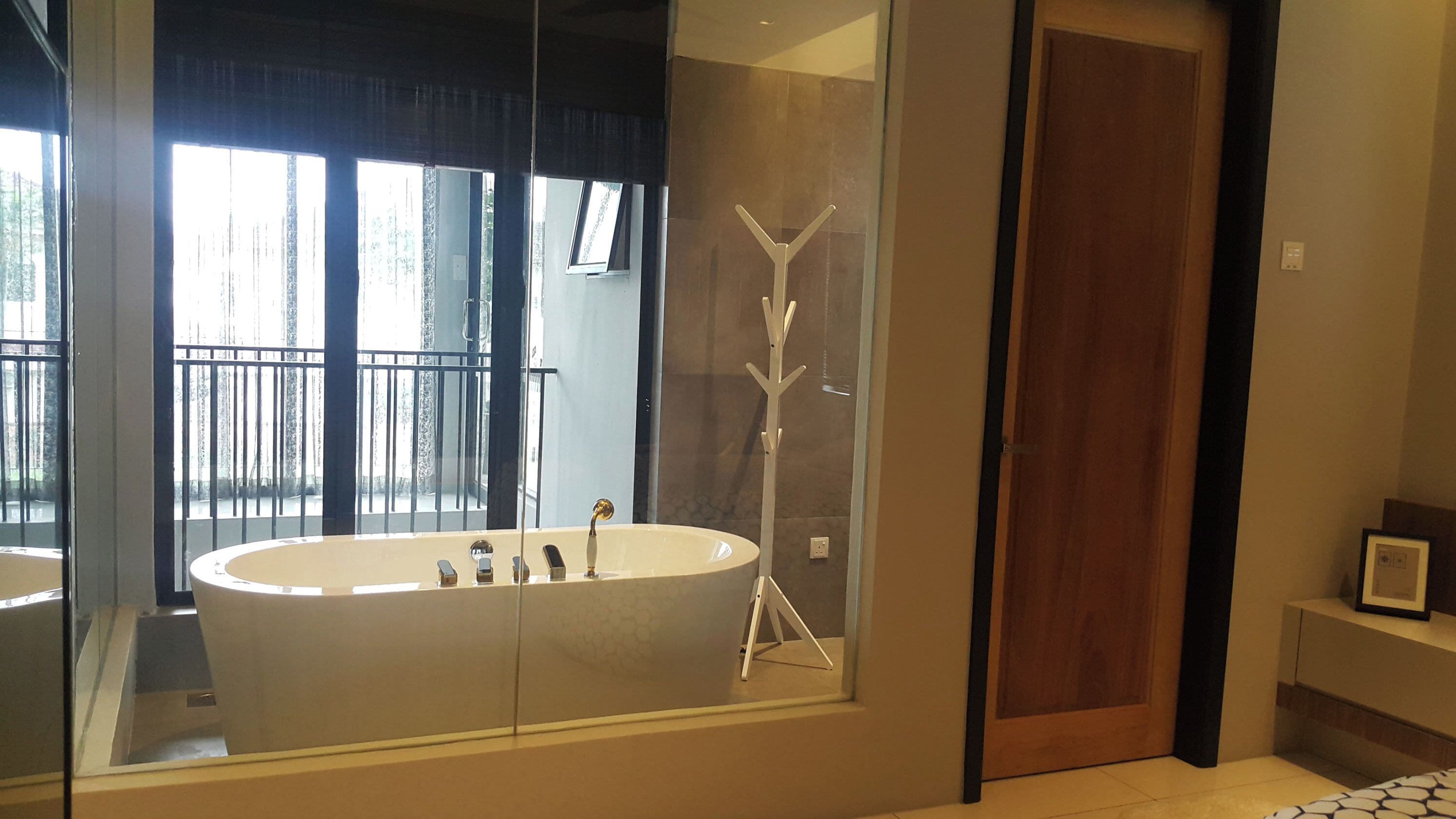 Un baño moderno con una bañera independiente, cabina de ducha con paredes de vidrio y una puerta de madera.
