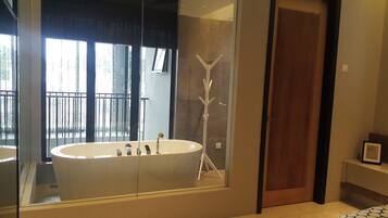 Un baño moderno con una bañera independiente, cabina de ducha con paredes de vidrio y una puerta de madera.
