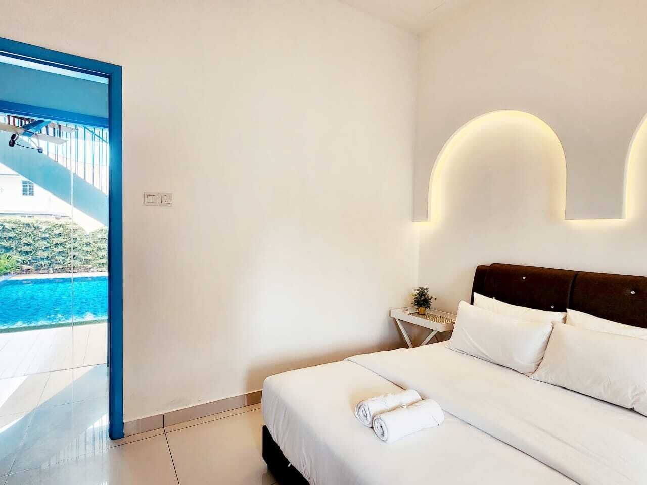 A modern hotel room with a large bed, a nightstand, and a view of a swimming pool.