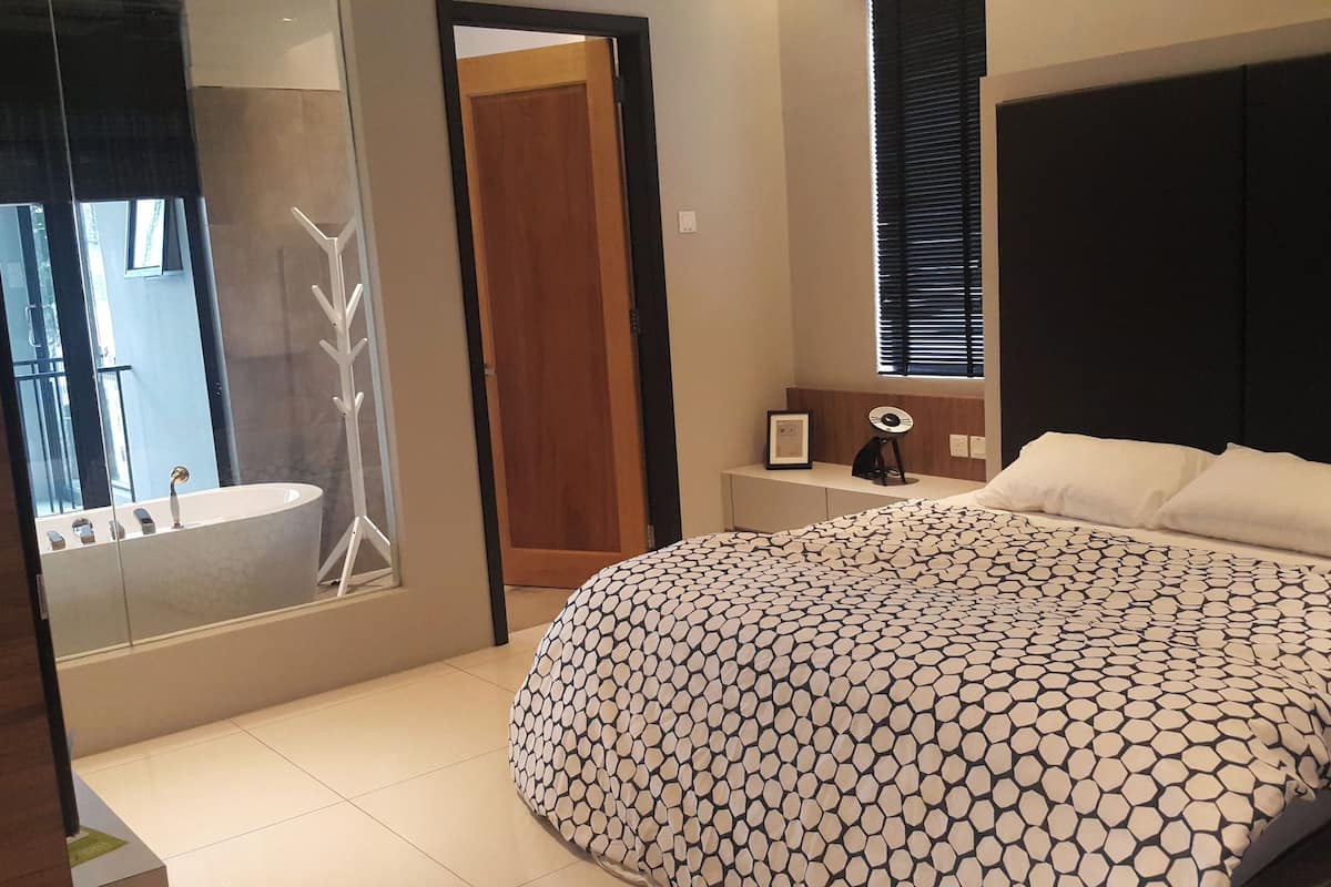Ein modernes Schlafzimmer mit einem großen Bett, einem Nachttisch, einem Spiegel und einer Tür zu einem Badezimmer.