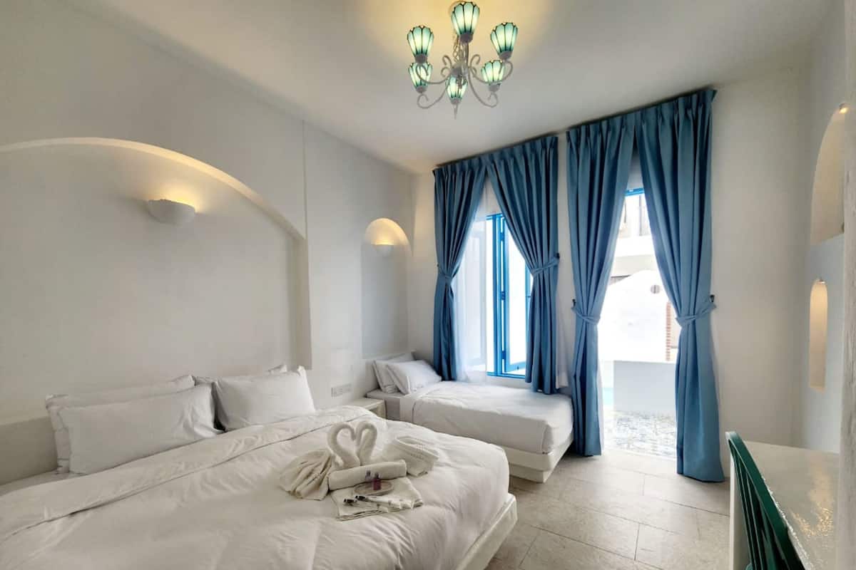Ein Hotelzimmer mit zwei Betten, einer Kristallleuchter und Blick ins Freie.