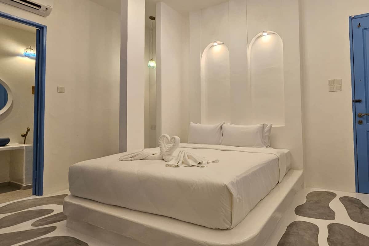 Ein modernes Schlafzimmer mit einem Bett, einer blauen Tür und einem Badezimmer mit Waschbecken und Spiegel.