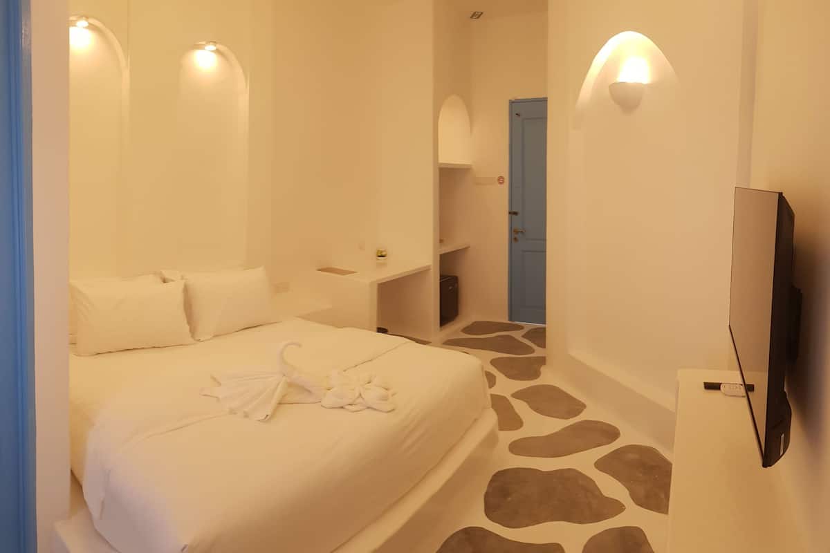 Ein Hotelzimmer mit Bett, Fernseher, Nachttisch und einer Badezimmertür.