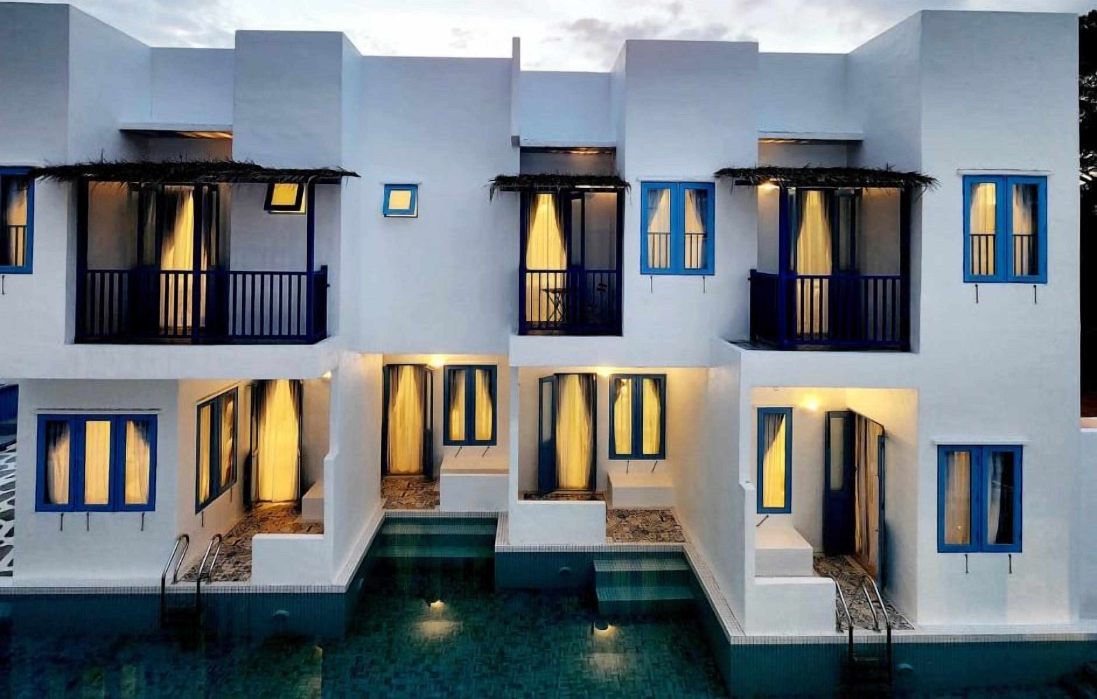 A multi-story building with balconies and a pool in front.
