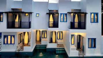 A multi-story building with balconies and a pool in front.